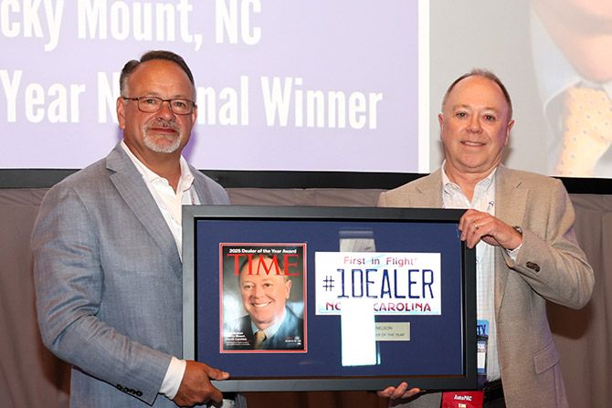 Convention Recognitions - Two men in business attire holding a large plaque