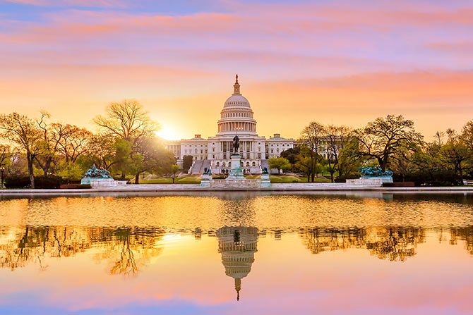 Thank You PAC Contributors! The U.S. Capitol building at sunrise, with a vibrant sky reflecting in the foreground pool. Trees frame the scene, creating a peaceful, majestic ambiance.
