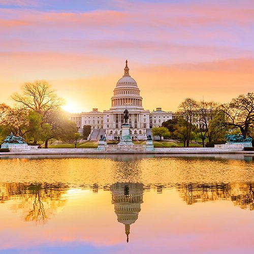 Fuel the Fight with NCADA AutoPAC; U.S. Capitol at sunset with a vibrant sky reflected in the pool. Trees frame the building, creating a serene and majestic atmosphere.