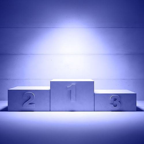 President’s Message: The Wins You Don’t See; Blue-tinted podium with numbers 1, 2, and 3 on steps. Central spotlight highlights the first place step, conveying achievement and focus.